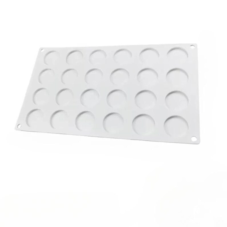 Op de afbeelding: Witte siliconen bakvorm met 24 ronde holtes.