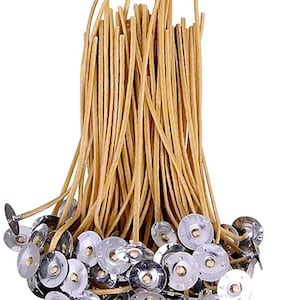 Könnte beinhalten: Ein Bündel Kerzendochte mit Metalllaschen. Die Dochte sind hellbraun und gerade und schlank. Die Metalllaschen sind silberfarben und rund, um die Dochte beim Kerzenmachen zu fixieren.