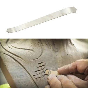 May include: A silver metal sculpting tool with a curved, elongated shape and a decorative pointed end. The tool is shown in use, carving a textured pattern into a clay sculpture. The image highlights the tool's design and its application in the art of sculpting.