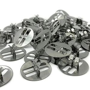 Può includere: Un mucchio di fibbie scorrevoli in metallo argentato con un design a doppia barra. Le fibbie sono rotonde e hanno un piccolo anello di metallo sul retro.