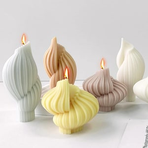 May include: A selection of decorative candles in pastel shades of yellow, pink, and white. The candles are shaped like bulbs with vertical ridged detailing. Each candle has a lit wick, creating a warm atmosphere. The candles are suitable for home decor.