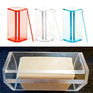 Può includere: Tre stampi per sapone in plastica trasparente, uno rosso, uno trasparente e uno blu. Gli stampi sono progettati per creare saponette rettangolari. Una saponetta è mostrata in uno degli stampi.