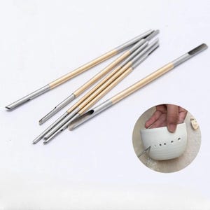 May include: Set of six gold and silver metal tools with different shaped tips for making holes in clay. The tools are shown on a white surface. A close-up image shows a hand using one of the tools to make a hole in a white ceramic pot.