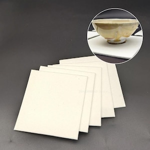 May include: A set of six white felt pads, ideal for protecting surfaces from scratches. The pads are square shaped and are stacked on top of each other.