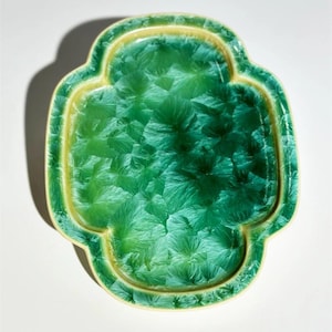 Könnte beinhalten: Eine grüne Keramikschale mit einem gewellten Rand und einer strukturierten Oberfläche. Die Schale hat einen hellgelben Rand.