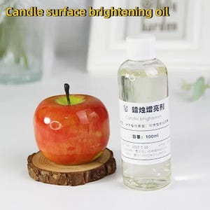 May include: A clear glass bottle with a white label that reads "Candle brightener" in English and Chinese. The bottle contains a clear liquid and is sitting on a white surface. The bottle is 100 ml.