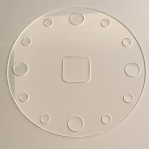 May include: A clear, circular acrylic piece with a square cutout in the center and evenly spaced circular cutouts around the perimeter. The transparent design allows light to pass through, creating a minimalist aesthetic.