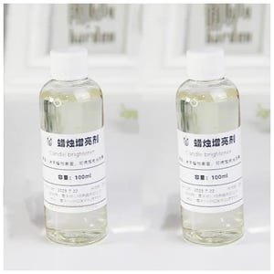 May include: Two clear glass bottles with white labels and white caps. The labels have black text that reads "蜡烛增亮剂 Candle brightener 容量: 100ml 2023 7 22".