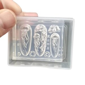 Puede incluir: Moldes de silicona transparente para arte de u&ntilde;as con dise&ntilde;os de medusas. Los moldes est&aacute;n en una caja de pl&aacute;stico transparente, sostenida por una mano. Los dise&ntilde;os incluyen varias formas de medusas y el texto japon&eacute;s "Magic Department Room".