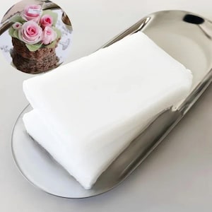 May include: Two white sheets of wax paper on a silver tray. The wax paper is folded in half and the edges are slightly curled.
