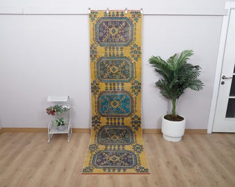 Könnte beinhalten: Ein gelber, blauer und violetter Läufer mit geometrischem Muster. Der Läufer hängt an einer Wand.
