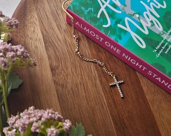 Marcador de livros com pingente de cruz e strass: design minimalista, acessório para leitores que prezam pela fé.
