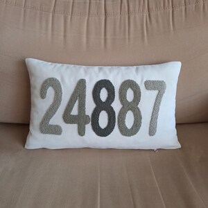 May include: White cushion with the number 24887 embroidered in grey and white thread.