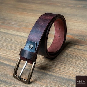 May include: A brown leather belt with a silver buckle. The belt has a distressed look and is made of high-quality leather.