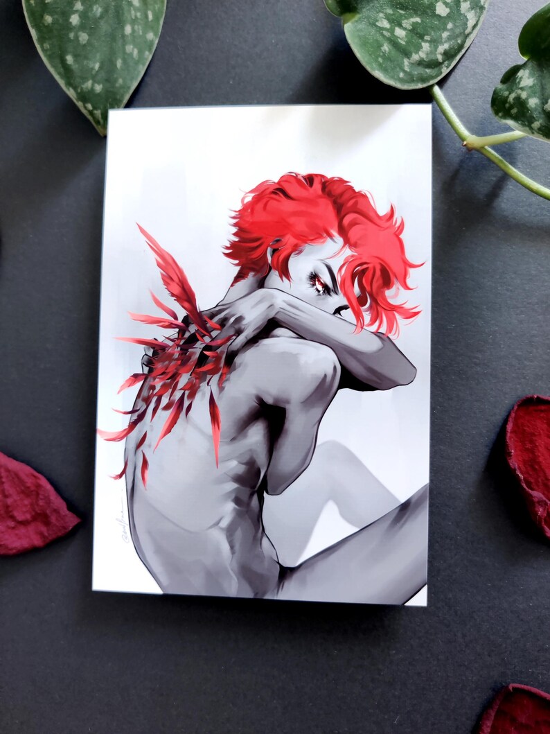May include: Grayscale art print showing a figure with vibrant red hair and feather-like details. The figure is in a seated position, arms wrapped around the body. The artwork has a dramatic and artistic style.