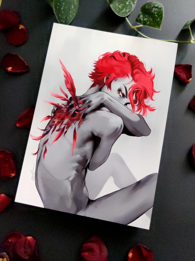 May include: A grayscale art print depicting a figure with red hair and red feather-like details on the back. The figure is seated, arms crossed. Red rose petals are scattered around the print.