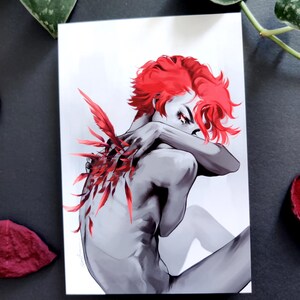 May include: A grayscale art print depicting a figure with striking red hair and red feather details. The figure is seated, arms crossed. The artwork has a dramatic, artistic style, with a focus on form and colour.