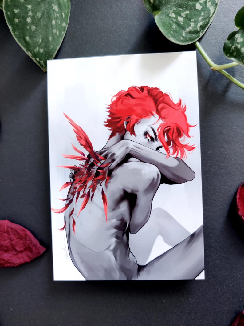 May include: A grayscale art print depicting a figure with striking red hair and red feather details. The figure is seated, arms crossed. The artwork has a dramatic, artistic style, with a focus on form and colour.