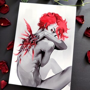 May include: A grayscale art print depicting a figure with bright red hair and red feather details on the back. The figure is seated, arms crossed. Red rose petals are scattered around the print, creating a dramatic effect.