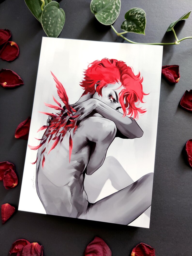 May include: A grayscale art print depicting a figure with bright red hair and red feather details on the back. The figure is seated, arms crossed. Red rose petals are scattered around the print, creating a dramatic effect.