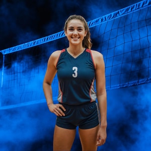 May include: A smiling volleyball player wearing a navy blue uniform with red and gray accents and the number 3. The background features a volleyball net and blue smoke.
