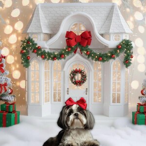 Könnte beinhalten: Festliche Weihnachtsszene mit einem weißen Haus mit roter Schleife, Girlande und Kranz. Zwei dekorierte Weihnachtsbäume flankieren das Haus, und ein Shih Tzu-Hund mit roter Schleife sitzt davor. Grüne Geschenkboxen sind vorhanden.