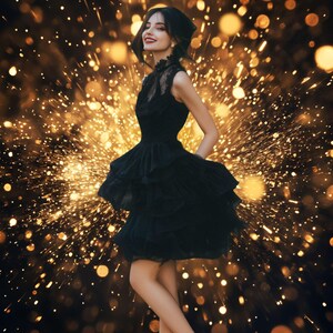 Puede incluir: Una mujer con un vestido negro con falda en capas y detalles de encaje sonríe sobre un fondo de luces doradas bokeh. El vestido tiene un corpiño ajustado y una falda acampanada con volantes, combinada con tacones negros.