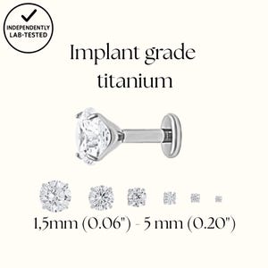 Puede incluir: Un labret de titanio de grado implante, de color plateado, con una gema redonda y transparente. La imagen incluye el texto "Implant grade titanium" y tamaños de 1,5 mm a 5 mm.