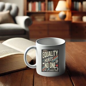 May include: White ceramic coffee mug with a black rim. The mug has a graphic design with the text "Equality Hurts No One" and the words "Unity & Diversity" at the bottom.