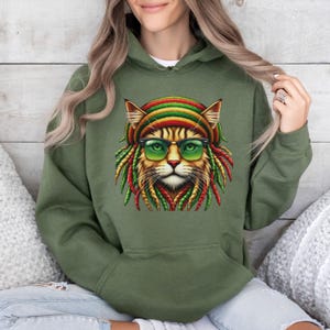 Peut inclure: Un sweat-shirt à capuche vert avec un motif représentant un chat portant un chapeau rouge, jaune et vert et des lunettes de soleil. Le chat a des dreadlocks.