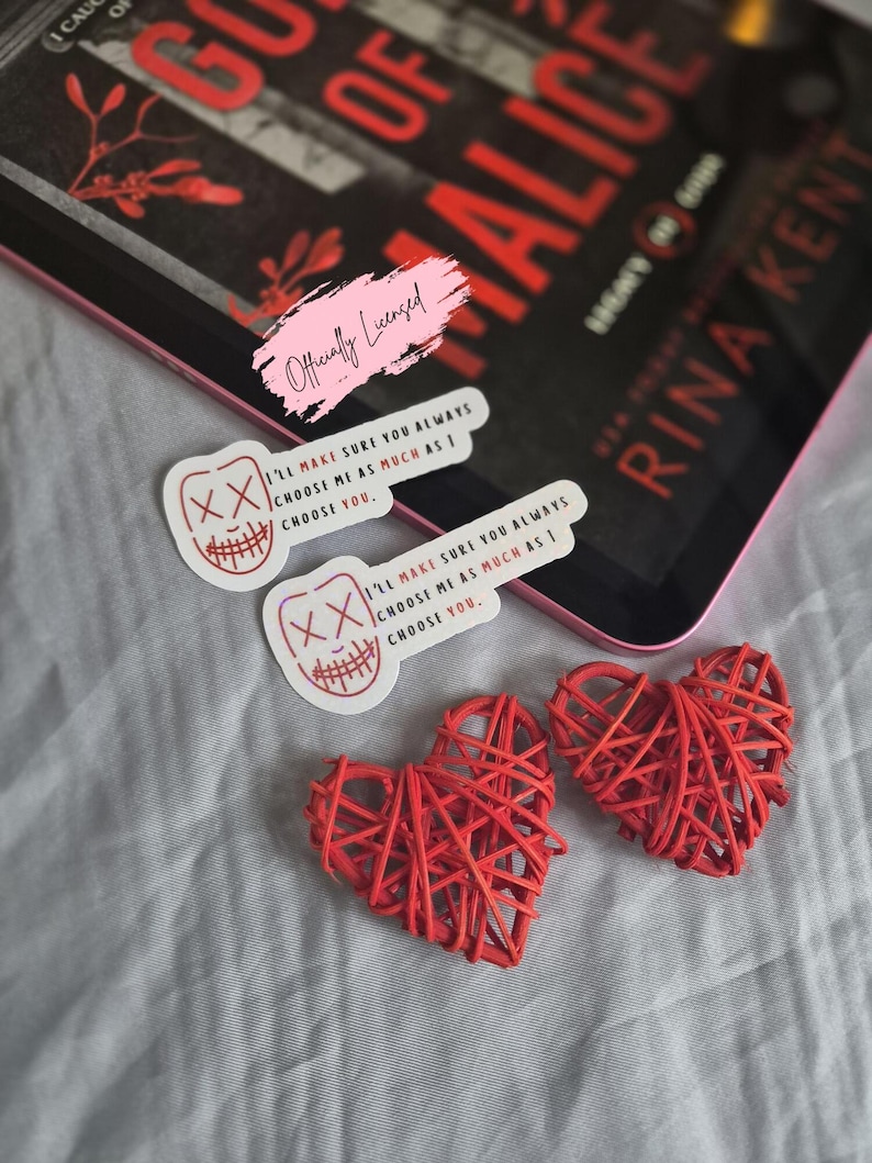 May include: An image featuring a book titled "Gods of Alice" by Rina Kent, accompanied by two stickers with a graphic design and the text "I'LL MAKE SURE YOU ALWAYS CHOOSE ME AS MUCH AS I CHOOSE YOU." Two red woven hearts are also present.