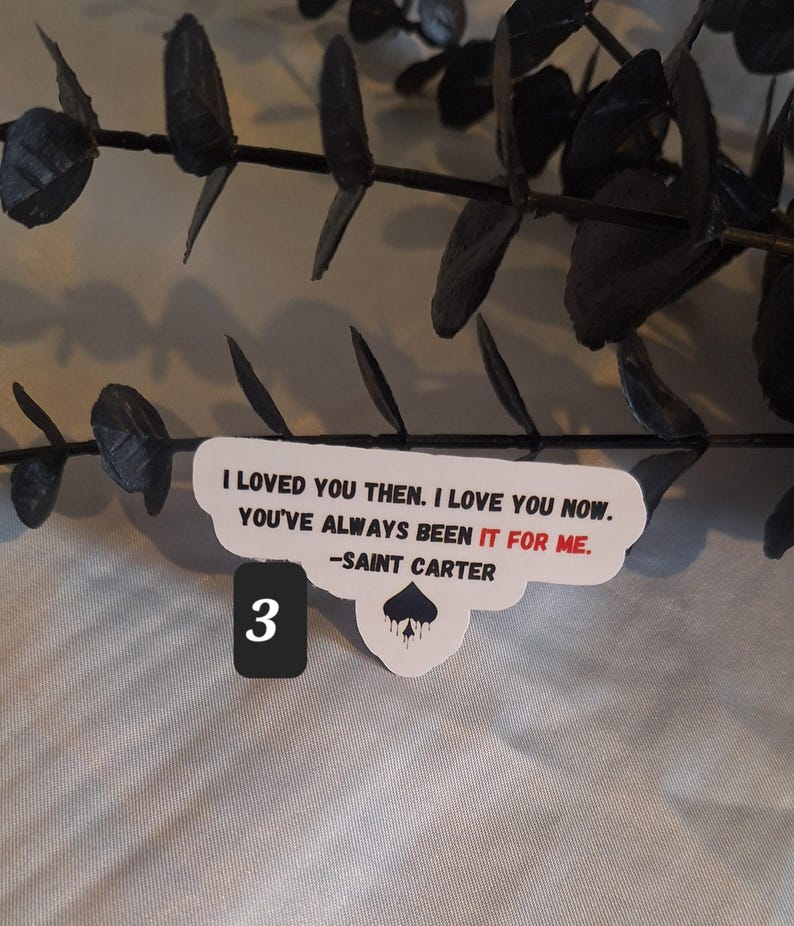 May include: White sticker with black text that reads "I loved you then. I love you now. You've always been it for me. -Saint Carter" with a black spade symbol dripping with black paint. The number 3 is written in black on a white background.