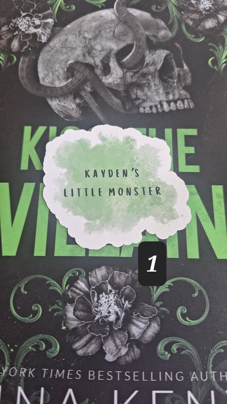 May include: A book cover with a skull and snake design, with the text "KAYDEN'S LITTLE MONSTER" in a cloud-shaped graphic. The background is black with green accents and floral illustrations.