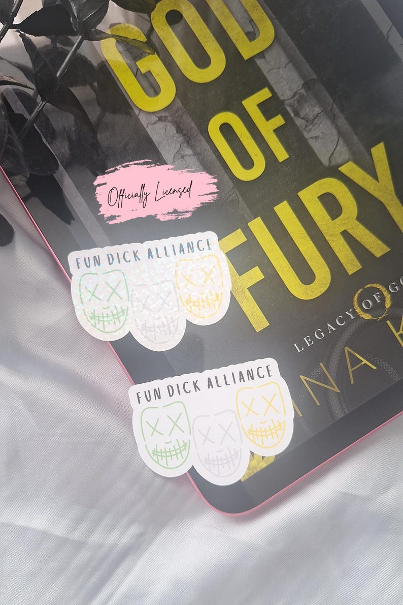 May include: Stickers with the text "FUN DICK ALLIANCE" and a mask design in green, white, and yellow. The stickers are on a book with the title "GOD OF FURY" and the text "Officially Licensed".
