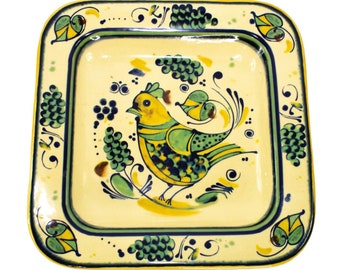 May include: A yellow ceramic square serving dish with a green, blue, and yellow bird design. The bird is surrounded by green grapes and leaves.