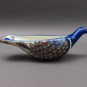 Könnte beinhalten: Eine weiße Keramik-Sauciere in Form eines Vogels mit einem blauen und violetten Blumendesign.