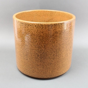 May include: A large, cylindrical ceramic planter with a speckled, brown glaze. The planter has a smooth, rounded bottom and a slightly flared top.