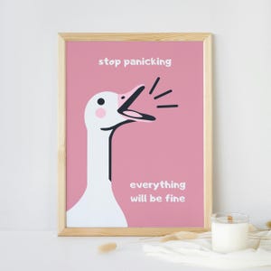 May include: A framed print featuring a cartoon goose against a pink backdrop. The goose is white with a black beak and neck. The print includes the text "stop panicking" and "everything will be fine".