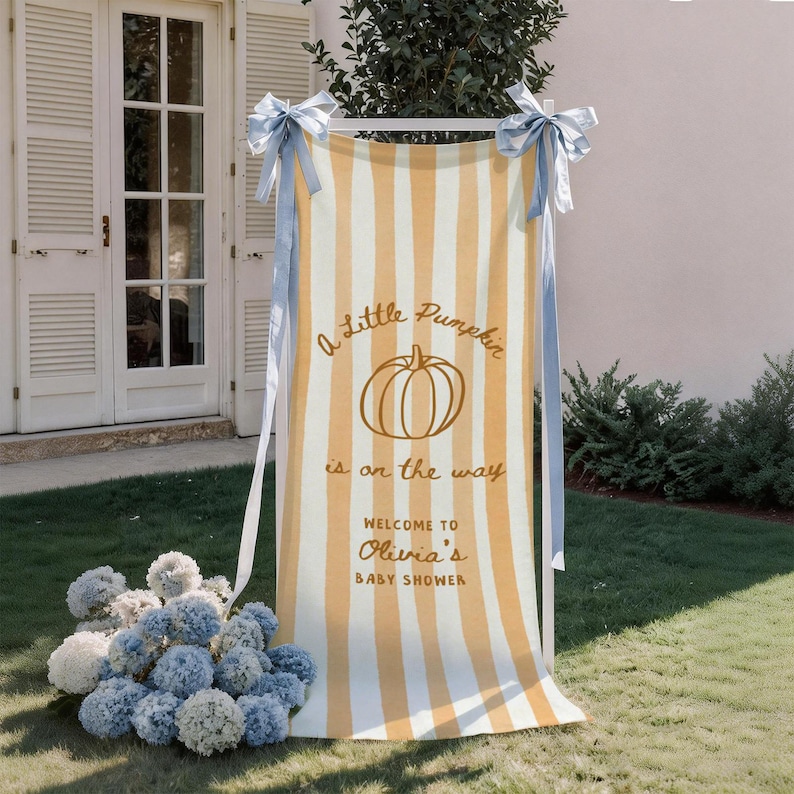 May include: A vertical rectangular banner featuring vertical light orange and white stripes, tied with light blue ribbons at the top corners. The text reads A Little Pumpkin is on the way, WELCOME TO Olivia's BABY SHOWER, with a pumpkin graphic.
