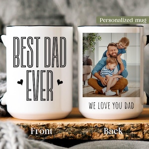 May include: White ceramic mug with a black handle and rim. The front of the mug reads "BEST DAD EVER" in bold, black letters. The back features a photo of a father and children with the text "WE LOVE YOU DAD".
