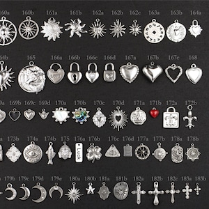 May include: A collection of silver-toned metal charms arranged in rows on a dark background, labelled with alphanumeric codes. A vertical ruler on the right side shows measurements in centimetres, ranging from 1 cm to 20 cm in total height.