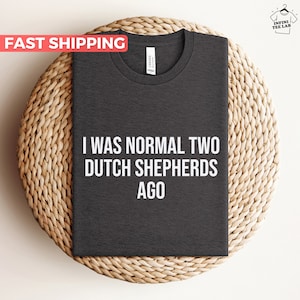 May include: Dark grey t-shirt with the text "I was normal two Dutch Shepherds ago" printed in white.