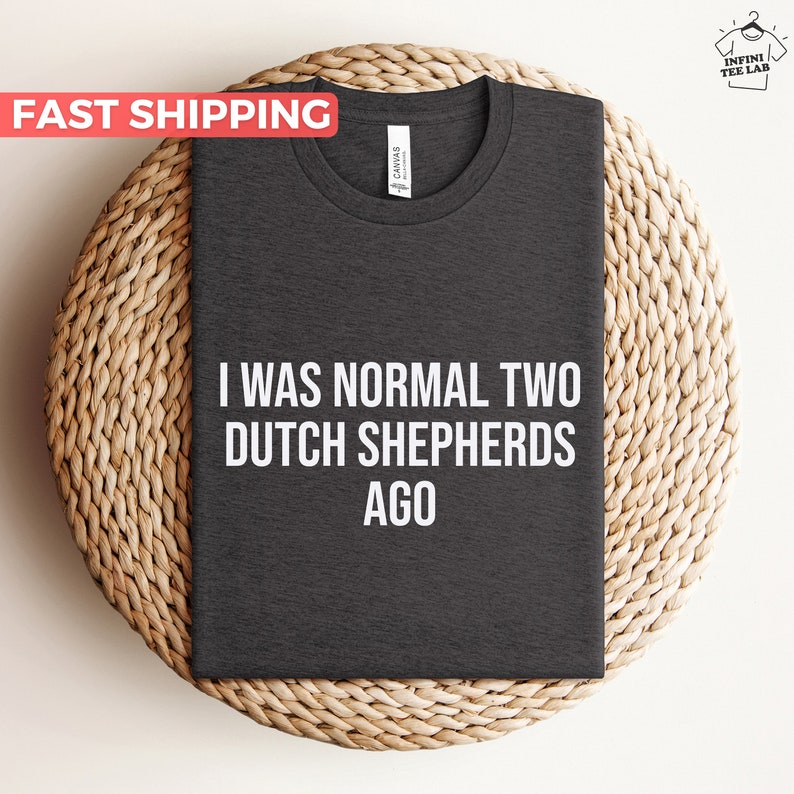 May include: Dark grey t-shirt with the text "I was normal two Dutch Shepherds ago" printed in white.