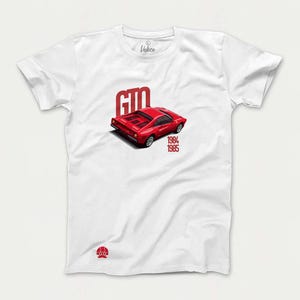 May include: White t-shirt with a red Ferrari GTO printed on the front. The car is a 1984-1985 model. The text "GTO" is printed above the car and the years "1984-1985" are printed below the car.