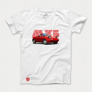 May include: White t-shirt with a red Mazda MX-5 Miata convertible printed on the front. The car is in a cartoon style with large eyes and a smiling expression. The text "MX5" is printed in red above the car.