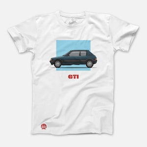 May include: White t-shirt featuring a teal-colored car illustration with red accents, set against a light blue square. The word "GTI" is printed in red below the car. The shirt has a crew neck and short sleeves.
