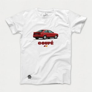 May include: White t-shirt with a red Audi Coupe car graphic and the word "Coupé" printed in red and orange.