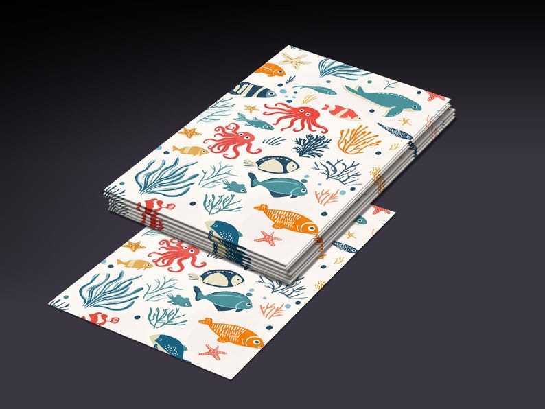 Op de afbeelding: Een stapel wit papier met een kleurrijk patroon van vissen, zeewier en zeesterren. Het patroon wordt op elk vel papier herhaald.
