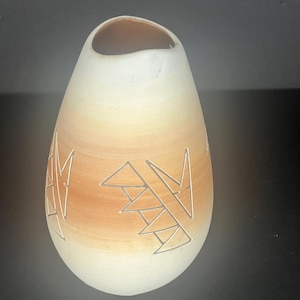 May include: A handcrafted, teardrop-shaped ceramic vase. The vase features a gradient of colors, transitioning from a creamy white at the base to a warm, earthy brown in the middle. Geometric patterns are etched into the brown section. The interior is a darker brown.