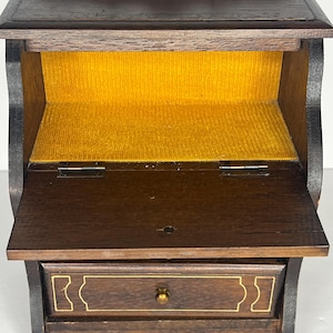 Puede incluir: Un peque&ntilde;o escritorio de madera con tapa abatible y un caj&oacute;n. El escritorio tiene un forro de terciopelo amarillo en el interior.